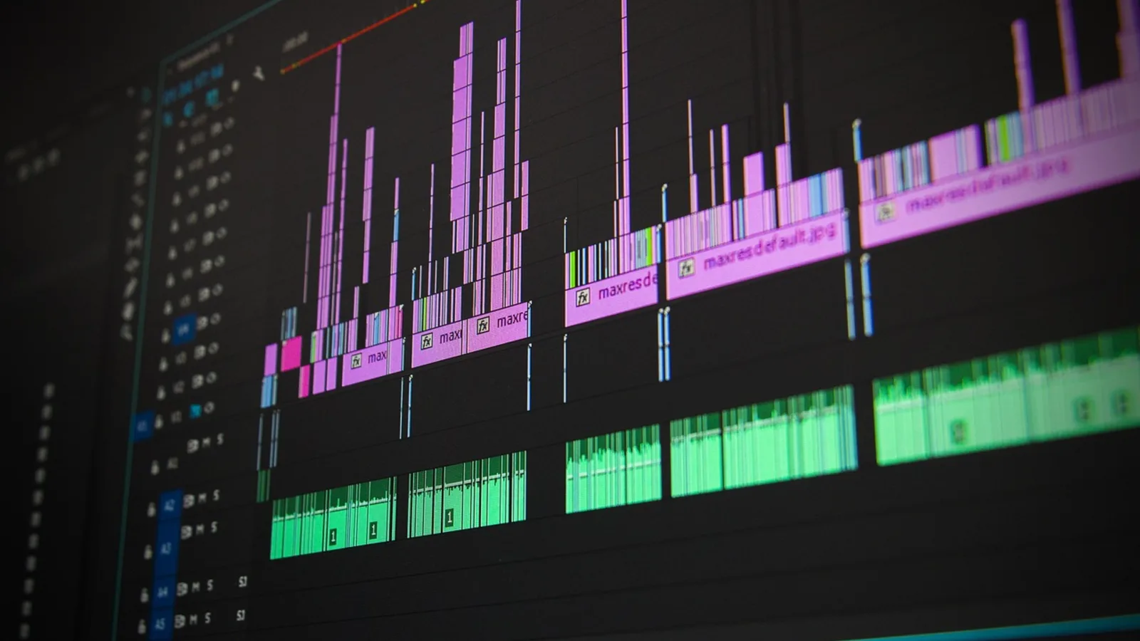 Schnitt-Timeline einer professionellen Videoproduktion mit zahlreichen Video- und Audiospuren auf einem Monitor in dunkler Umgebung.