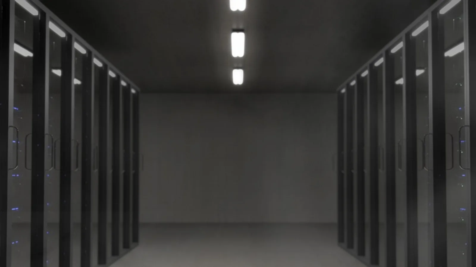 Dunkler Serverraum mit Reihen von Server-Racks und leuchtenden Statusanzeigen.